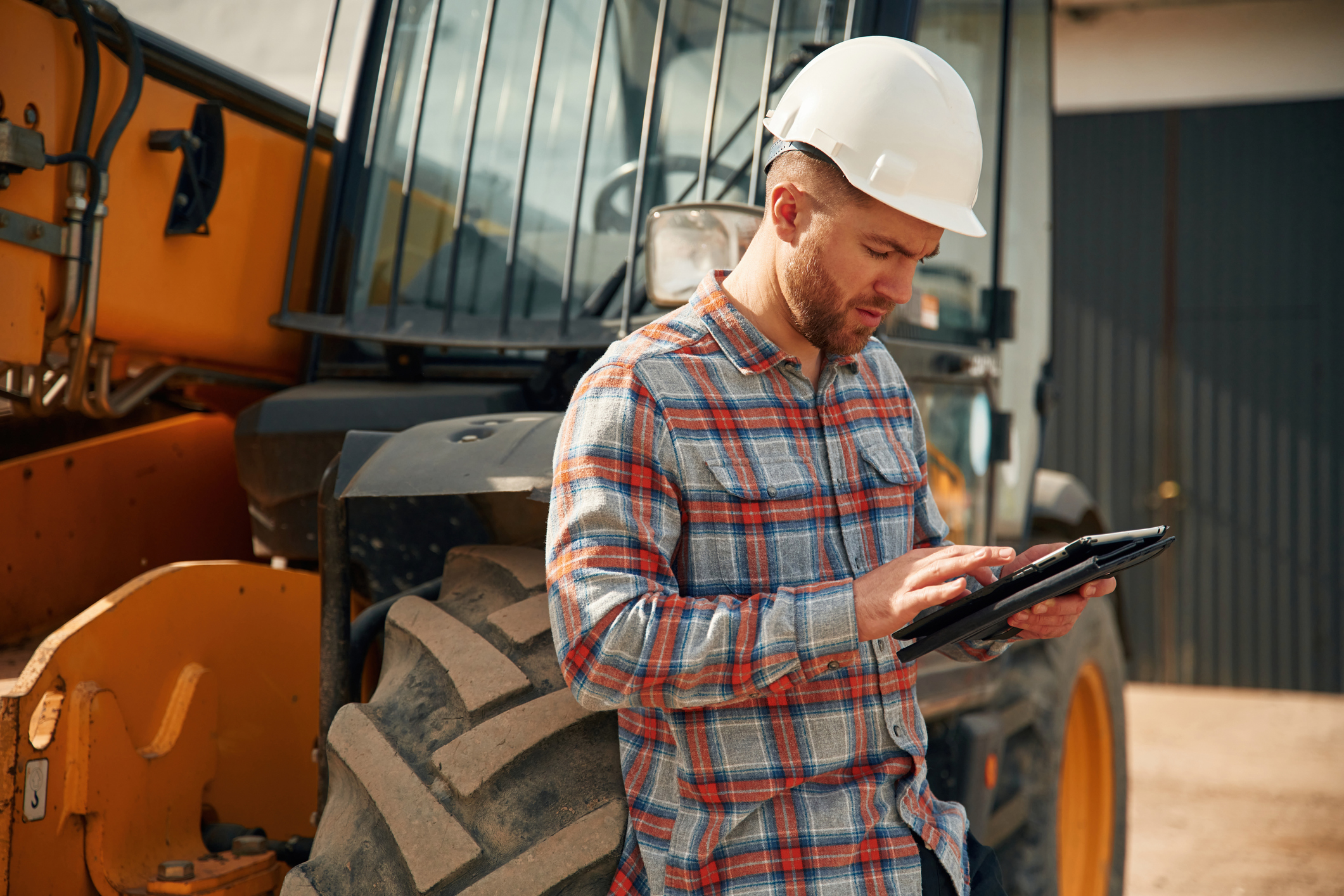 Construction worker using tablet to track heavy equipment on job site