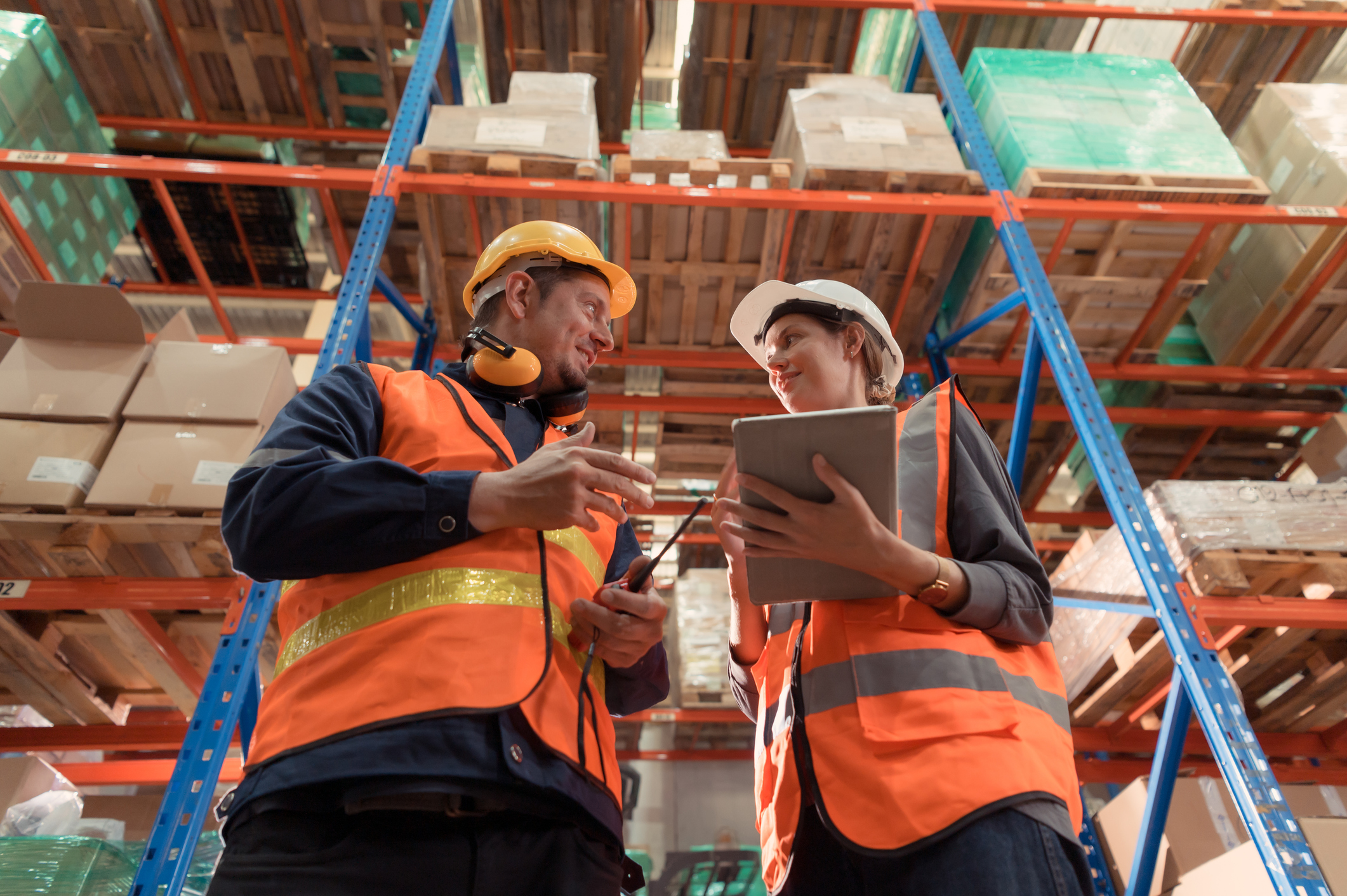 Warehouse workers in safety vests reviewing inventory on tablet
